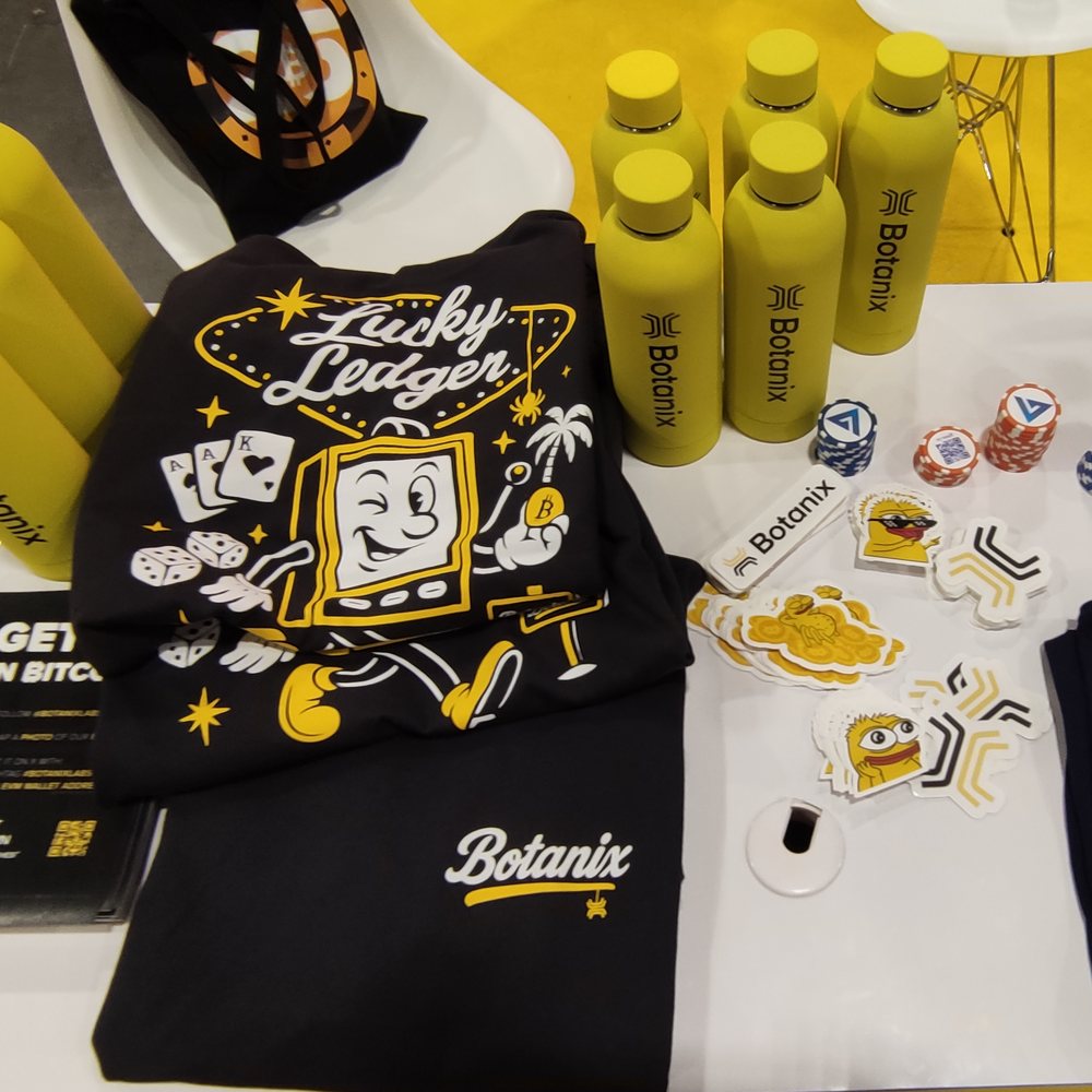 Lucky Ledger tee, bottles, caps and stickers on the merch table